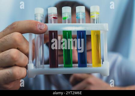 A scientist holding a rack of test tubes filled with colorful liquids, conducting a chemistry experiment in a laboratory. Research, scientific analysi Stock Photo