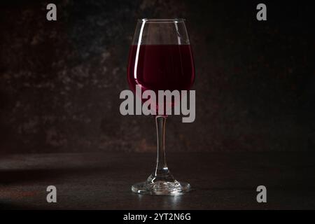 Front view of red wine glass on rusty ceramic surface against dark ceramic background Stock Photo