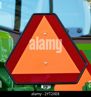 Close up orange reflective farm triangle safety sign for slow moving vehicles Stock Photo