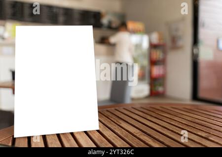 Mock up Label the blank menu frame in Bar restaurant ,Stand for booklets with white sheets paper acrylic tent card on wooden table cafeteria blurred b Stock Photo