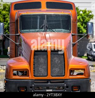 Repaired previously damaged and freshly painted after repair brown bonnet semi truck with disassembled front part of the cabin standing on the industr Stock Photo