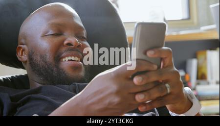 Front view of African american man using mobile phone in a comfortable home Stock Photo