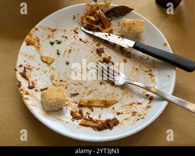 The remnants after eating a plate of boar ragu pasta and bread meal are shown on a table at a restaurant in Italy. Stock Photo