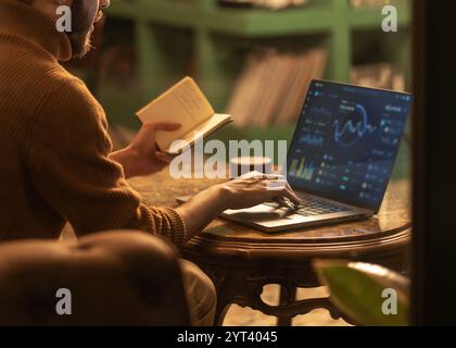 Professional trader reviewing stock market data and financial analytics on laptop while taking notes. Modern businessman analyzing trading charts in a Stock Photo