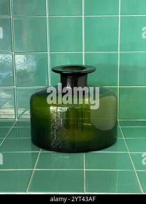 Green glass vase on green tiles surface. Stock Photo