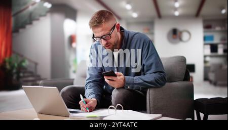 Man Calculating Finance Online On Couch At Home Stock Photo