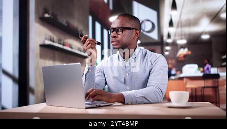 Man Drinking Coffee And Working On Laptop. Sending Voice Message On Phone Stock Photo
