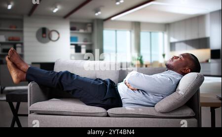 Young Man Relaxing On Sofa In Living Room Stock Photo