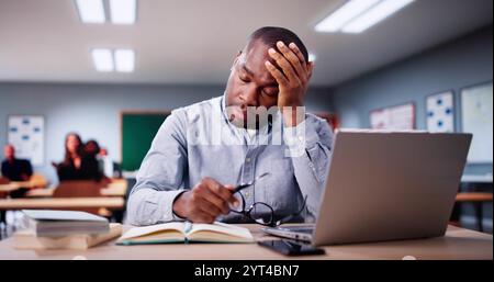 Bored Man In Classroom Using Computer Technology. Laptop In Education Stock Photo