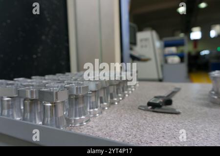 CNC-Machined Metal Parts on Inspection Table and Digital Vernier Caliper. Industrial scene, inspection table in a manufacturing facility background Stock Photo