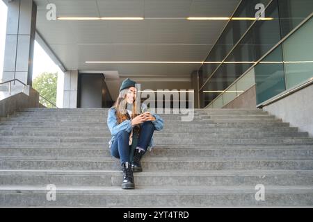 Smiling student using smartphone sitting on university steps Stock Photo