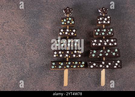 DIY edible Christmas trees made of waffles, chocolate and marshmallows, decorated with confectionery sprinkles on brown background Stock Photo