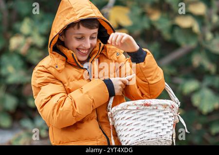 Boy in winter jacket holding basket and smiling Stock Photo