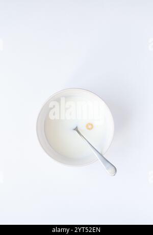 Bowl of milk with single cheerio cereal on white background. Stock Photo
