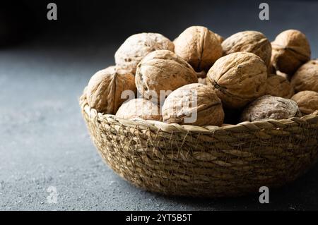 Ripe and raw whole big walnut kernel with Shell in wicker basket on rustic backdrop. healthy nut food for brain Stock Photo