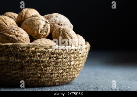 Ripe and raw whole big walnut kernel with Shell in wicker basket on rustic backdrop. healthy nut food for brain Stock Photo