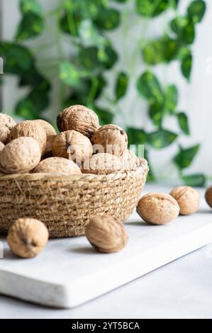 Ripe and raw whole big walnut kernel with Shell in wicker basket on rustic backdrop. healthy nut food for brain Stock Photo