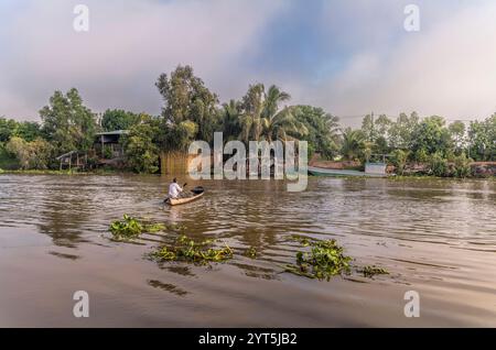 An old man on an inland canal in Vietnam early in the morning rowing home Stock Photo