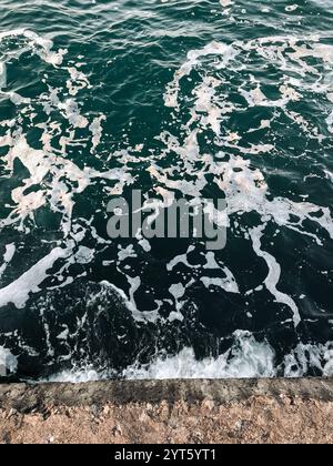 Sea water surface - waves on the sea. Splashes and texture on dark teal green water. Stock Photo