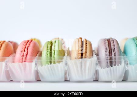 French Macarons with white paperpan in plastic transparent packaging box on gray background, colorful cakes with various flavors. appetizing dessert, Stock Photo