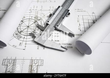 Caliper rests on rolled blueprints, highlighting the importance of precise measurements in engineering and design. Stock Photo