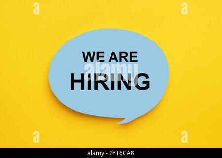 Paper note with text We Are Hiring on yellow background, top view. Human resource Stock Photo