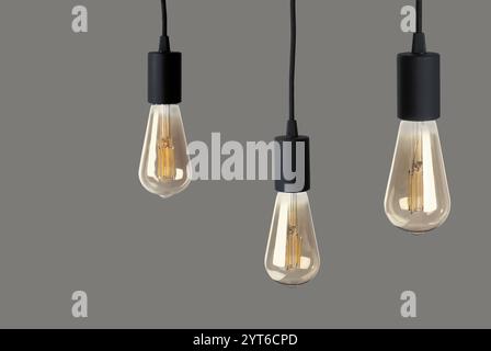 Three light bulbs hanging on grey background Stock Photo