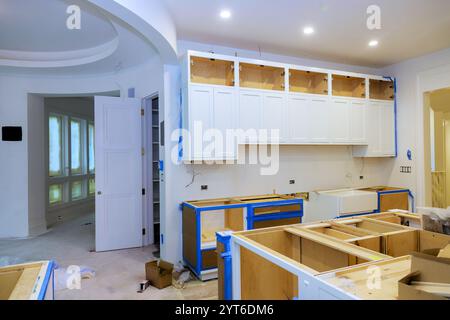 Workers are installing white cabinetry in modern kitchen renovation with an open layout design ample natural light. Stock Photo