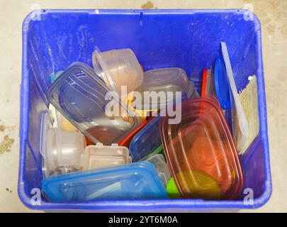 A blue box full of old and colorful discarded plastic food storage containers sits waiting to be recycled to keep them from landfill. Stock Photo