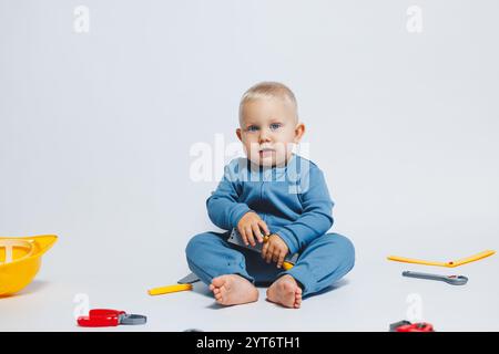 Baby boy on a white background plays with a plastic hammer. Children's set of tools for construction. Child plays with toys on a white background Stock Photo