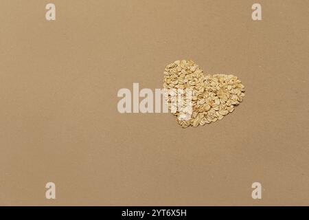 Oats in shape of heart care. Top view brown craft paper background with copy space Stock Photo