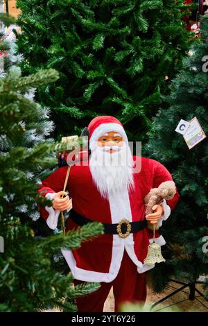 Santa Claus Figurine with Teddy Bear and Bell Under Christmas Tree Stock Photo