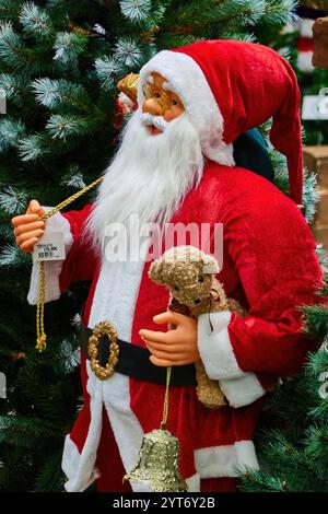 Santa Claus Figurine with Teddy Bear and Bell Under Christmas Tree Stock Photo