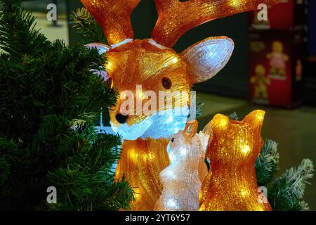 Festive Illuminated Deer and Squirrel Figures Amid Christmas Tree Decorations Stock Photo
