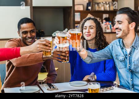 Cheerful multi-ethnic friends toasting with beer glasses while enjoying time together at brewery restaurant Stock Photo