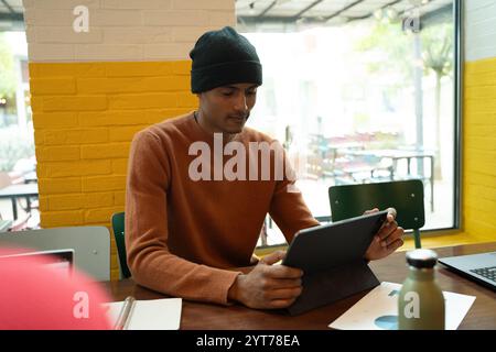 Focused young businessman using digital tablet while working remotely in cafe Stock Photo