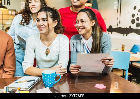 Young businesswomen and businessmen having a team meeting, discussing a business plan in a coworking space Stock Photo
