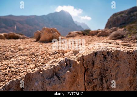 Cracked rough rock surface from limestone and coral in foreground, mountain in background. Crete, near Balos beach. Stock Photo
