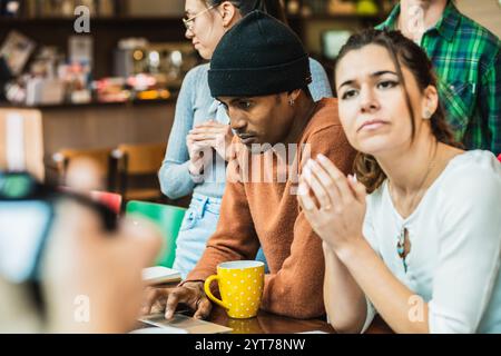 University students collaborating on a project in a cafe, using a laptop and engaging in discussion Stock Photo