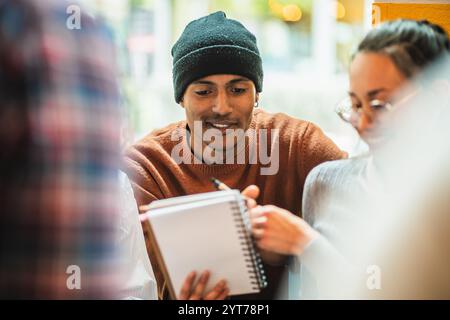 University students are collaborating on a project, sharing notes, and studying together in a cafe Stock Photo