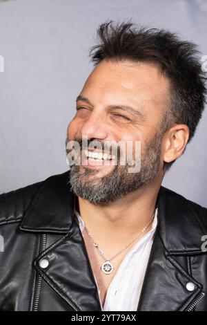 Portrait of a cheerful musician wearing a leather jacket, smiling and looking away from camera Stock Photo