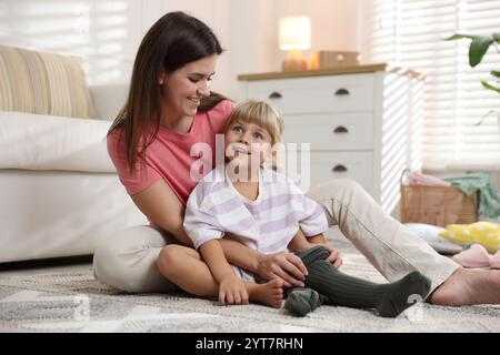 Mother helping her daughter to put tights on at home Stock Photo