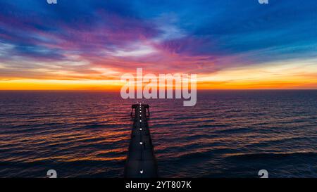 The pier reaching out to the ocean as the sunrises. Drone view from the end of the pier. Wrightsville Beach, NC Stock Photo