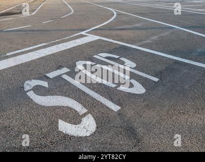 Stop sign white painted on the road asphalt with horizontal signs white painted stripes on the road Stock Photo