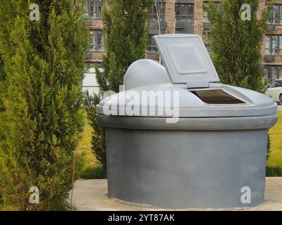 large gray plastic storage container standing in a residential courtyard among apartment buildings and green spaces, collection Stock Photo