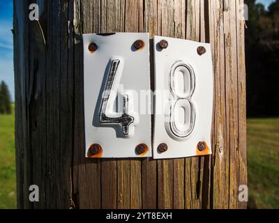 Close-up view of a wooden electricity pole with nailed numbers 4 and 8 made of punched sheet metal. Stock Photo