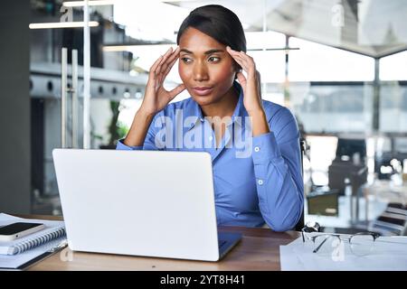 Stressed tired young African American business woman feeling headache at work. Stock Photo