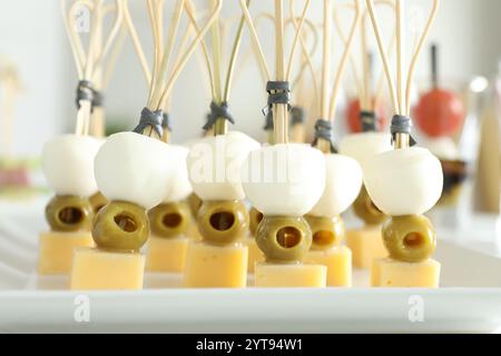 Tasty canapes with different types of cheese and green olives on white table, closeup Stock Photo