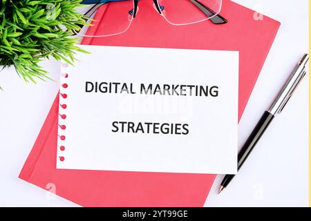 Business concept. words DIGITAL MARKETING STRATEGIES close-up, on a white sheet of notepad. Stock Photo