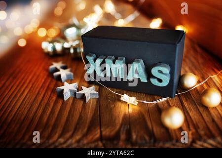 Christmas still life with a chain of star lights and a surprise gift on a rustic wooden table Stock Photo